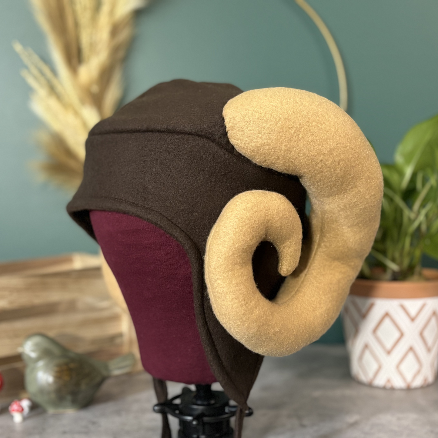 Brown and beige fantasy-style hat with large, curved ear-like decorations on a mannequin head.