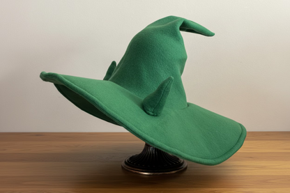 Green witch hat  with horns on a wooden surface with a neutral background